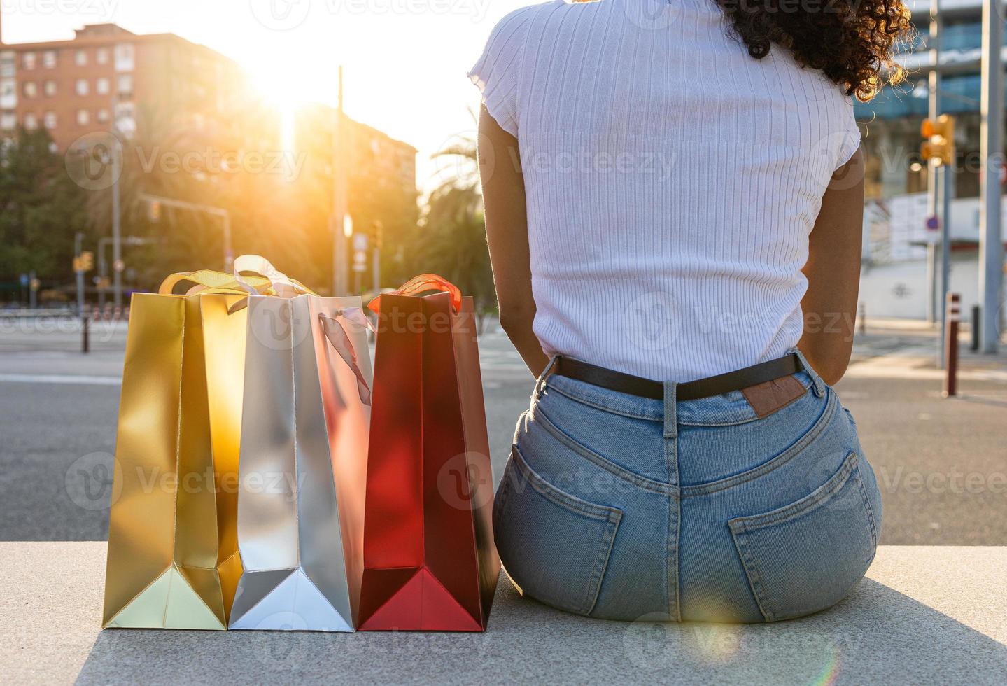 Female sitting next to the colorful shopping bags photo