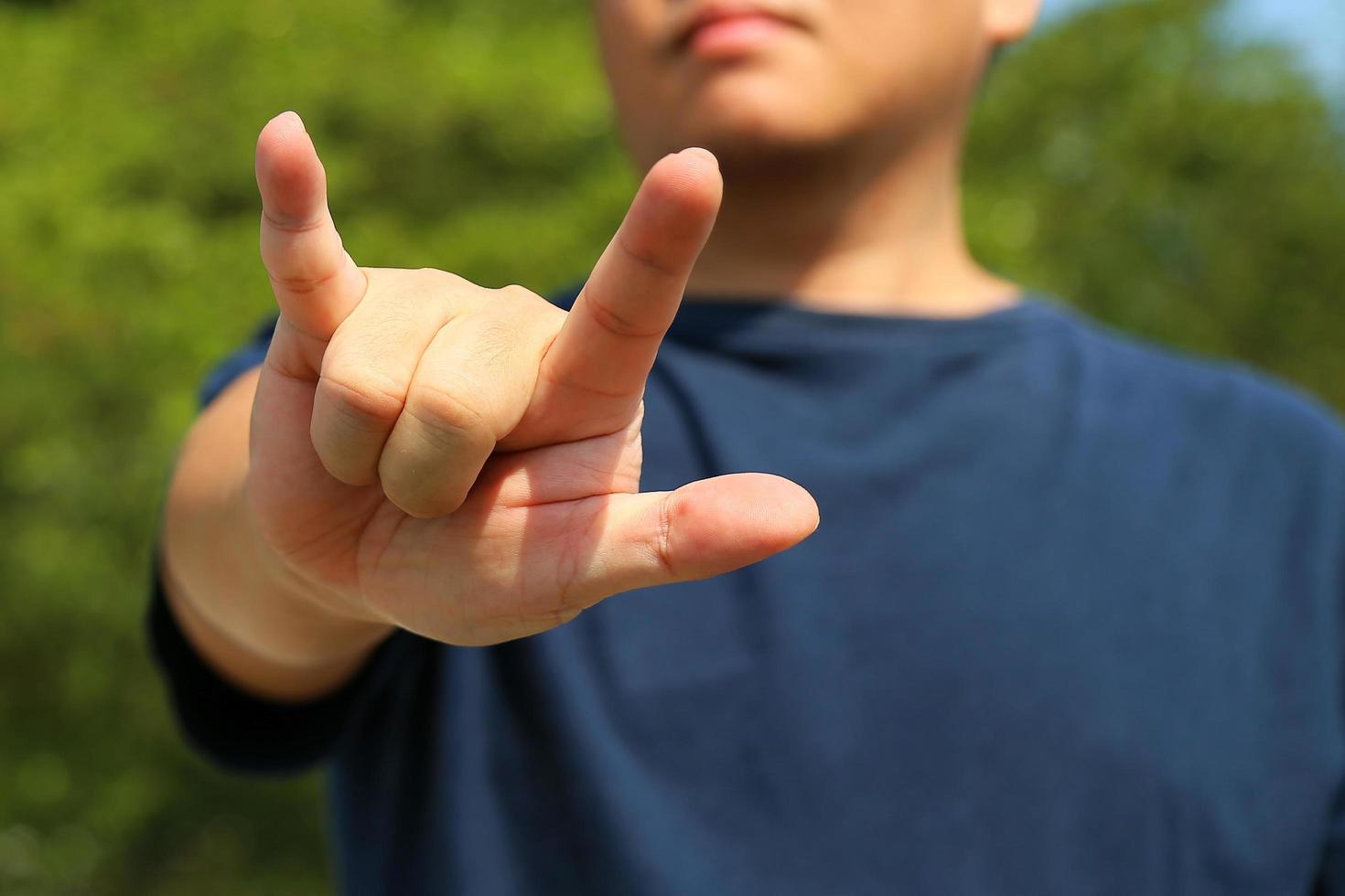 Man show the horn fingers with green leaves background. I love you symbol. photo