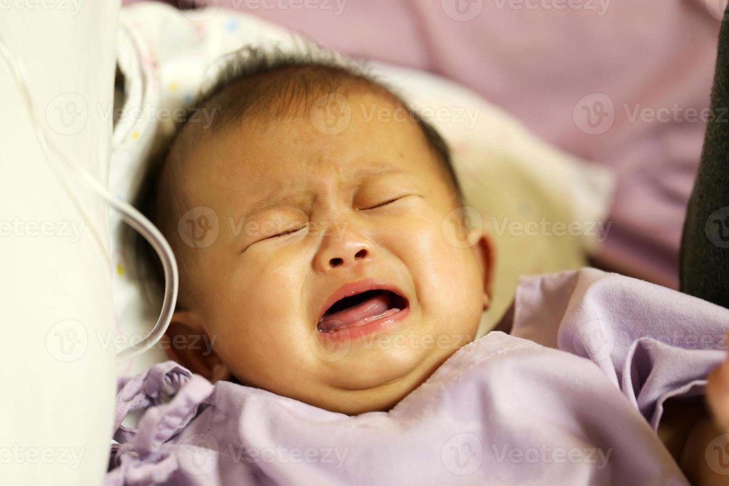 Sick asian baby in a hospital. Child got fever and crying in hospital. photo