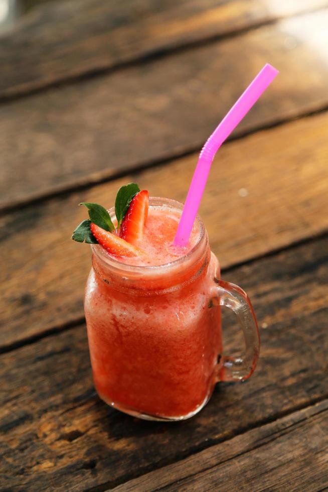 Glass of strawberry smoothie and fresh strawberries on top and have wooden background. Healthy food and drink concept. photo