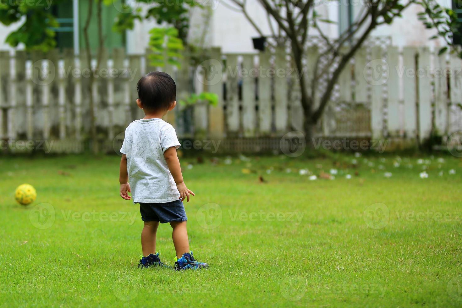 Asian boy playing football at the park. Kid with ball in grass field. photo