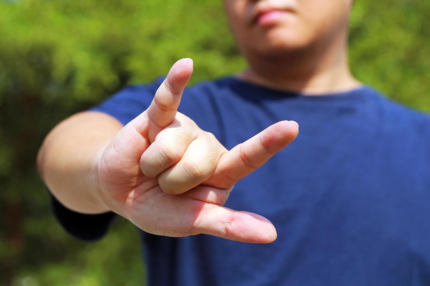 Man show the horn fingers with green leaves background. I love you symbol. photo