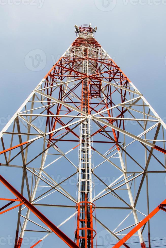 Mástil de telecomunicaciones con enlace de microondas y antenas transmisoras de televisión sobre un cielo azul. foto