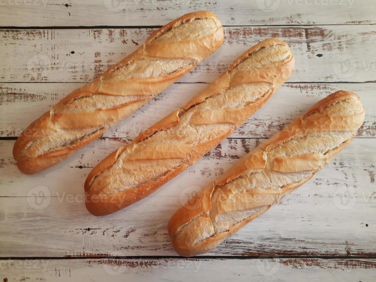 Three loaves of bread close-up on top of aged and white wooden countertop photo