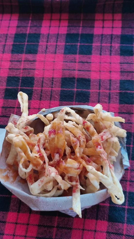 market snacks in the form of crispy fried crab sticks sprinkled with tomato sauce in a paper wrap photo