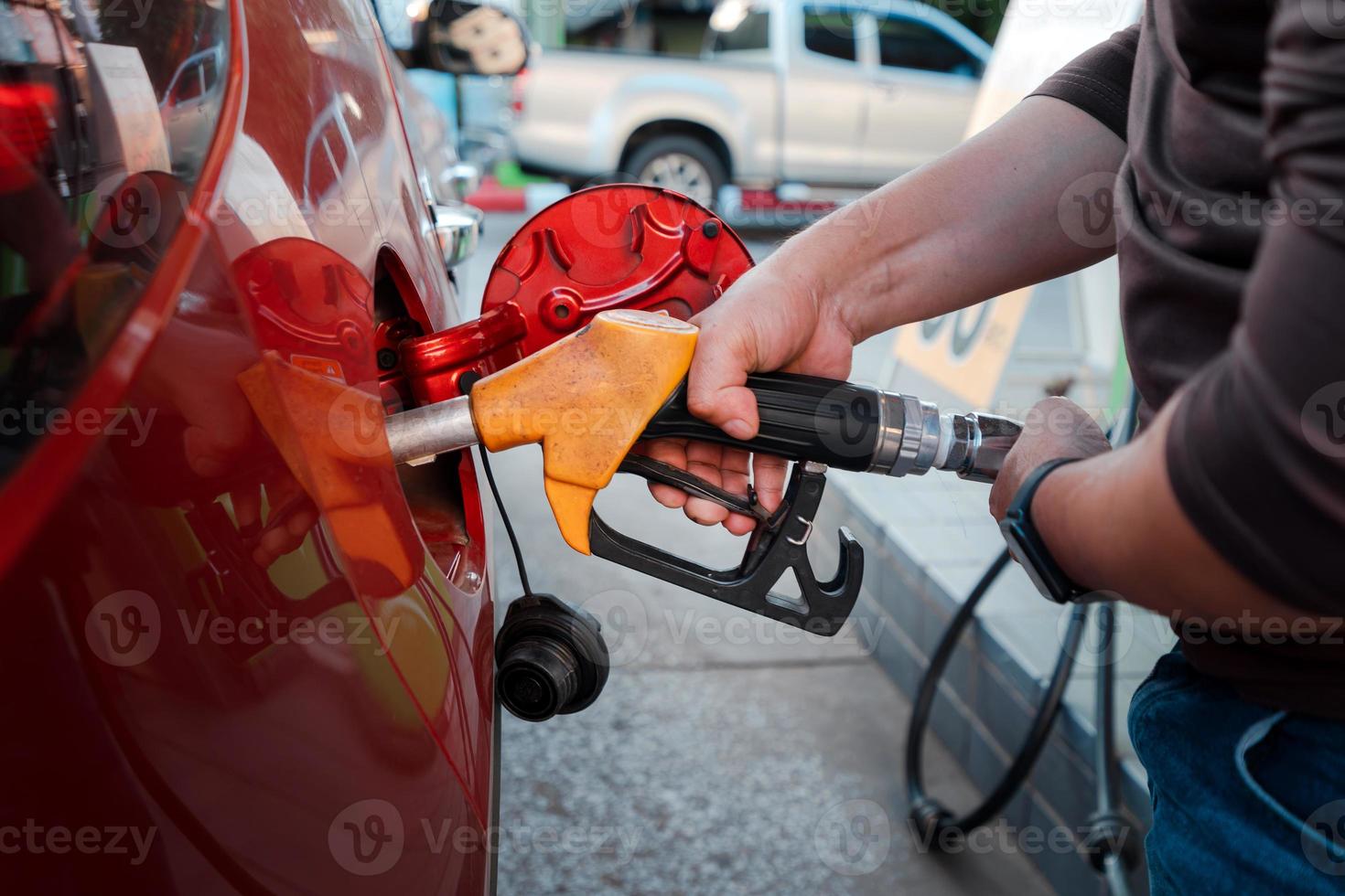 closeup man hands handle tool refueling gasoline pump into red car photo