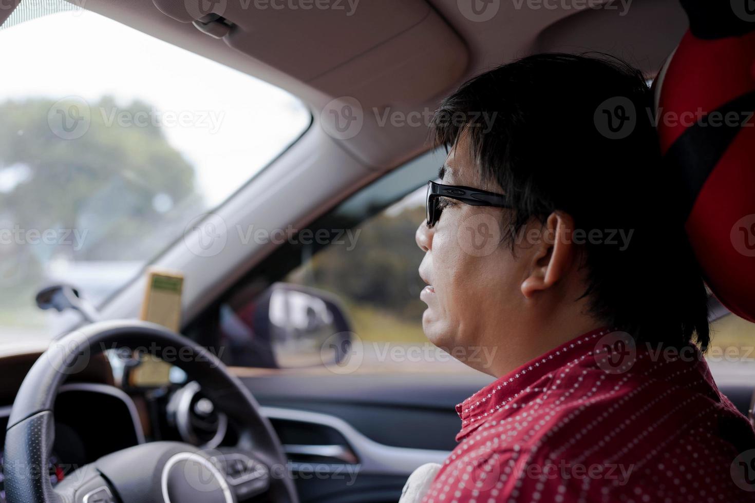 hombre asiático maduro con estrés o miedo o expresión facial triste durante sentarse y conducir un camión en el tráfico. navegador gps en el teléfono móvil. obtener la pérdida anteojos hombre en mal viaje foto