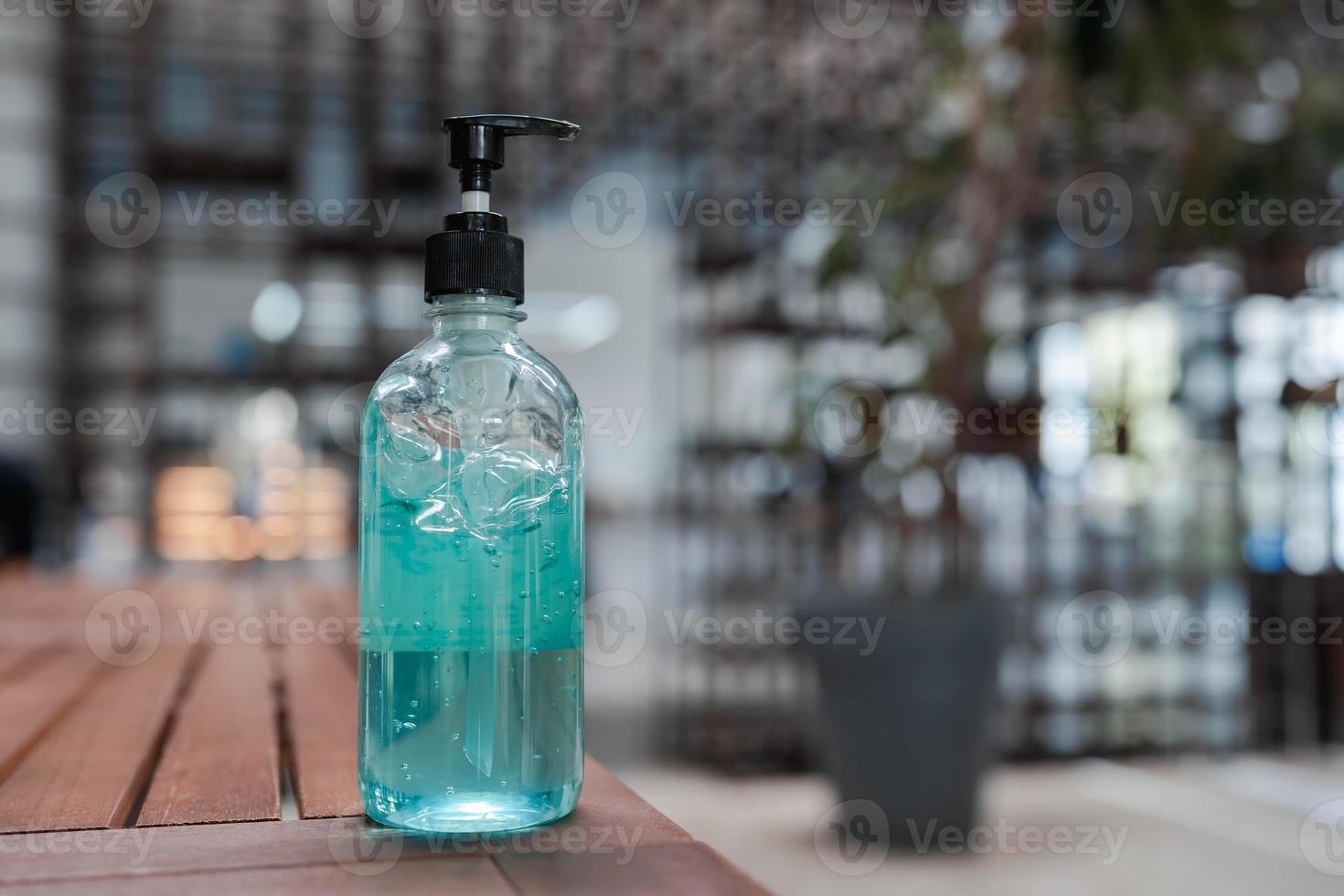 blue alcohol gel for hand sanitizer in transparent pumping bottle on wooden table with bokeh background. new normal. COVID-19 infection protection. photo