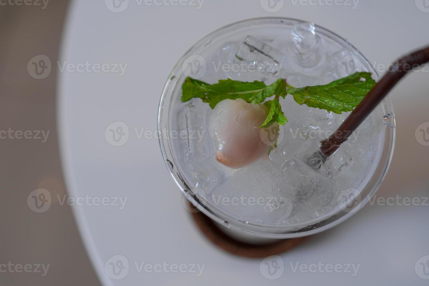 iced lychee soda topping decorated with fruit and mint leaf on white table photo