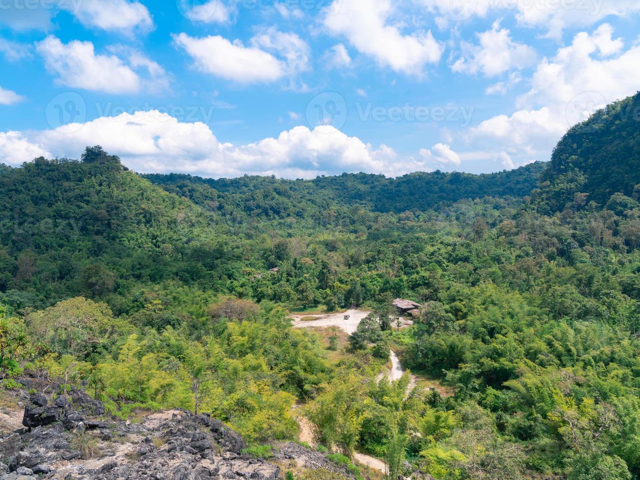 forest and road view with bright cloudy blue sky from above old mining rock mountain in Thong Pha Phum, Kanchanaburi, Thailand photo