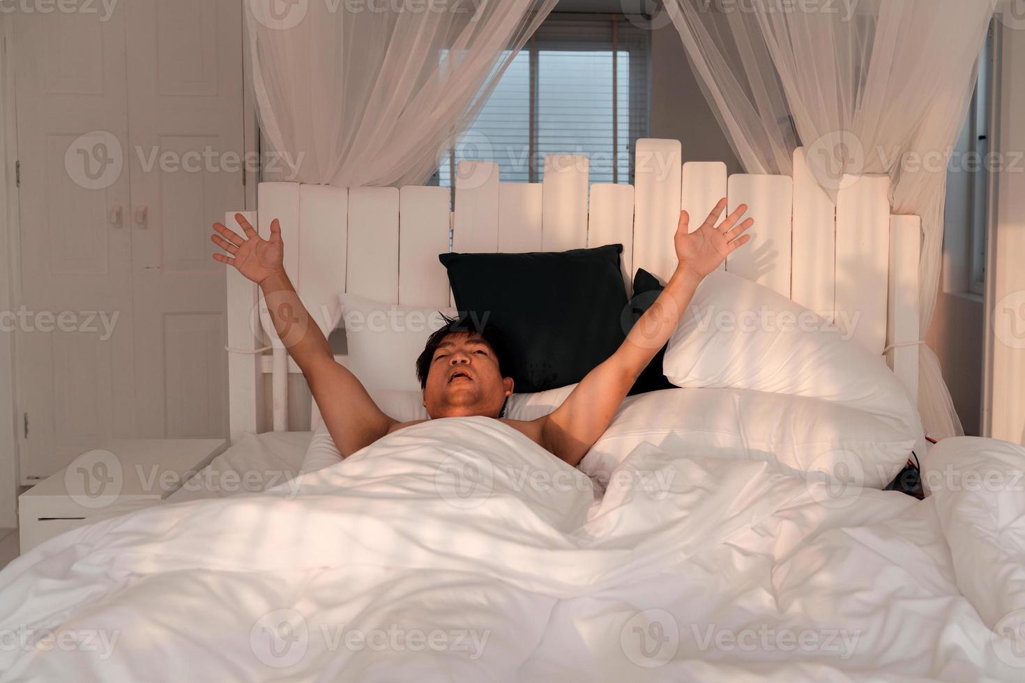 lazy man stretching after wakup in bed photo