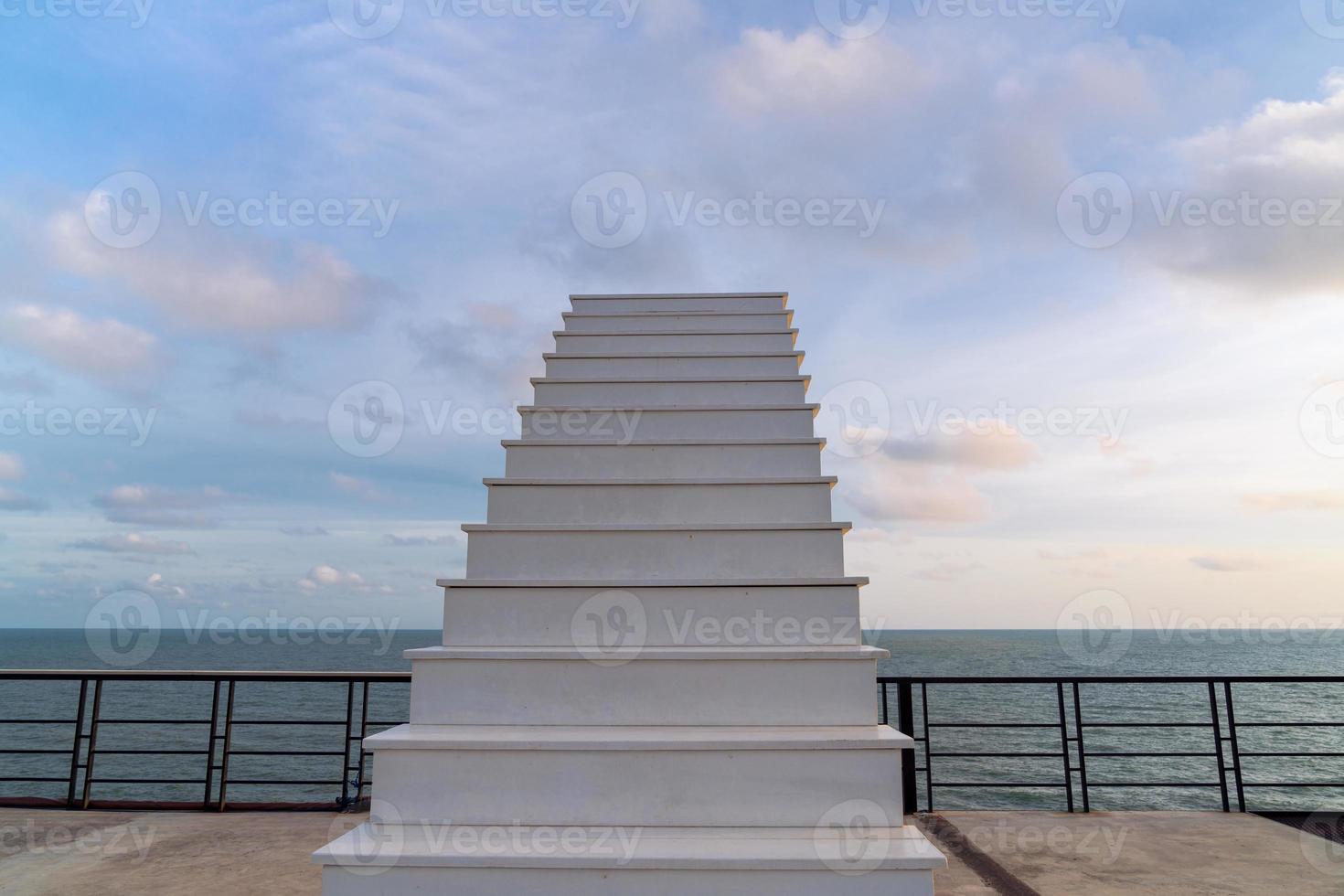 escalera de madera blanca al cielo en la terraza en la cima de la colina con vistas al mar por la noche con cielo nublado foto