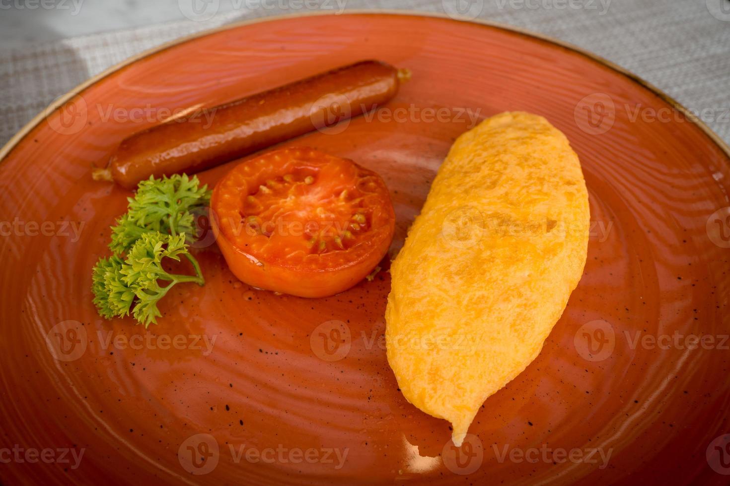 closeup fried omelet with roasted sausage and sliced tomato on dish, breakfast photo