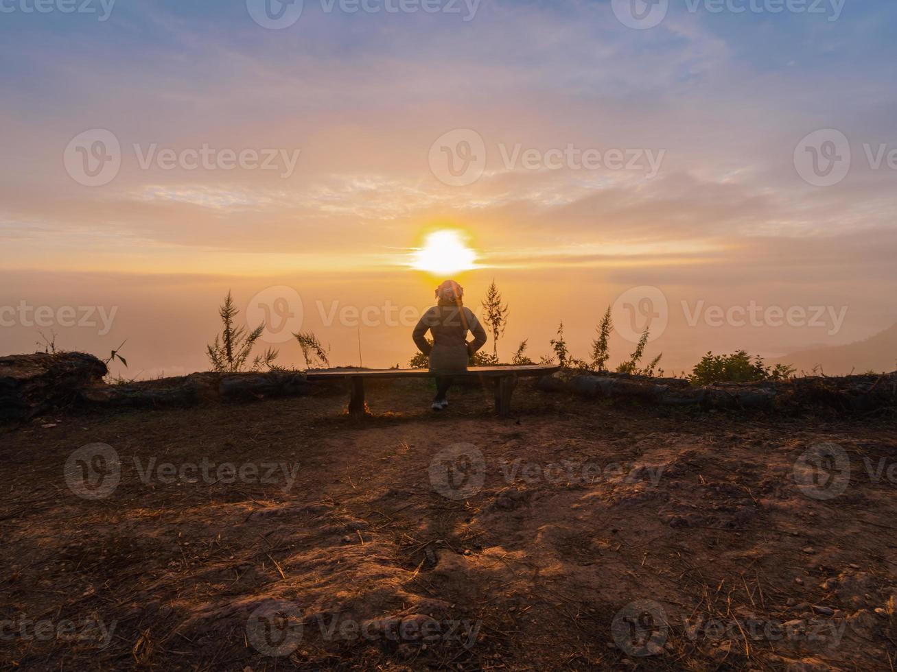 sunrise in fog cloudy sky on hill with sunlight ray at Phatang 104 viewpoint mountain peak with woman tourist sit and looking at view. travel in Chiang Rai, Thailand photo