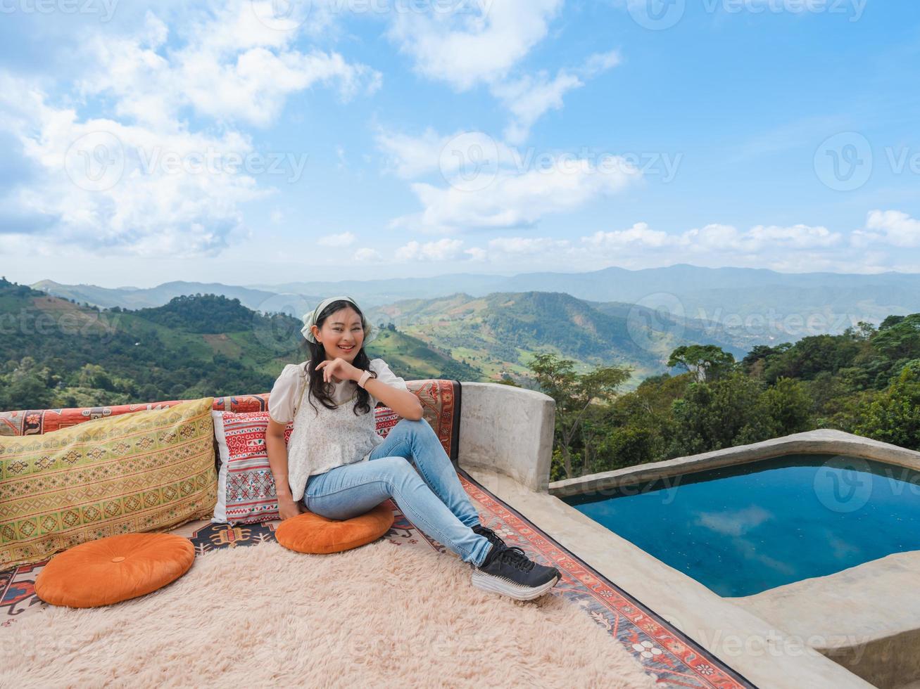 happy Asian woman sit and relax at balcony with mountain view with cloudy blue sky at Doi Chang, travel attraction in Chiang Rai photo