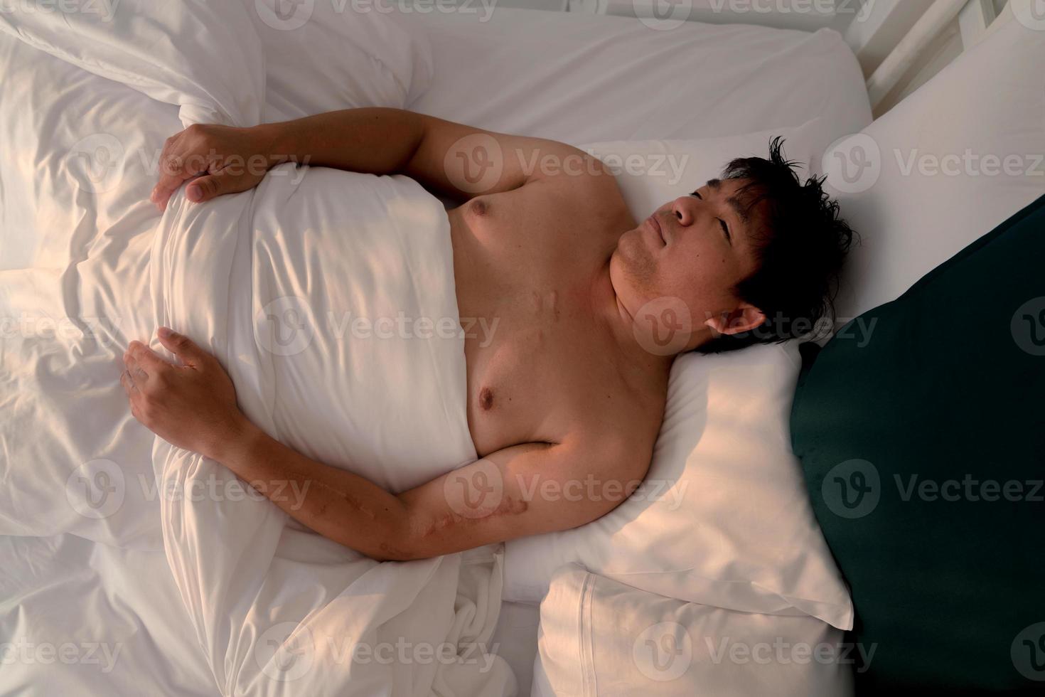 hombre asiático gordito durmiendo en la cama foto