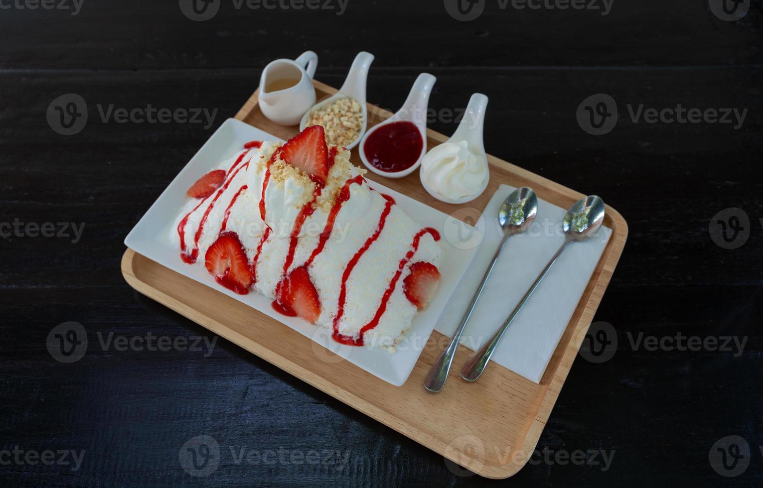 Strawberry kakigori or Japanese shaved ice dessert milk flavor or bingsu Korea dessert with strawberry sauce and toppings on table photo