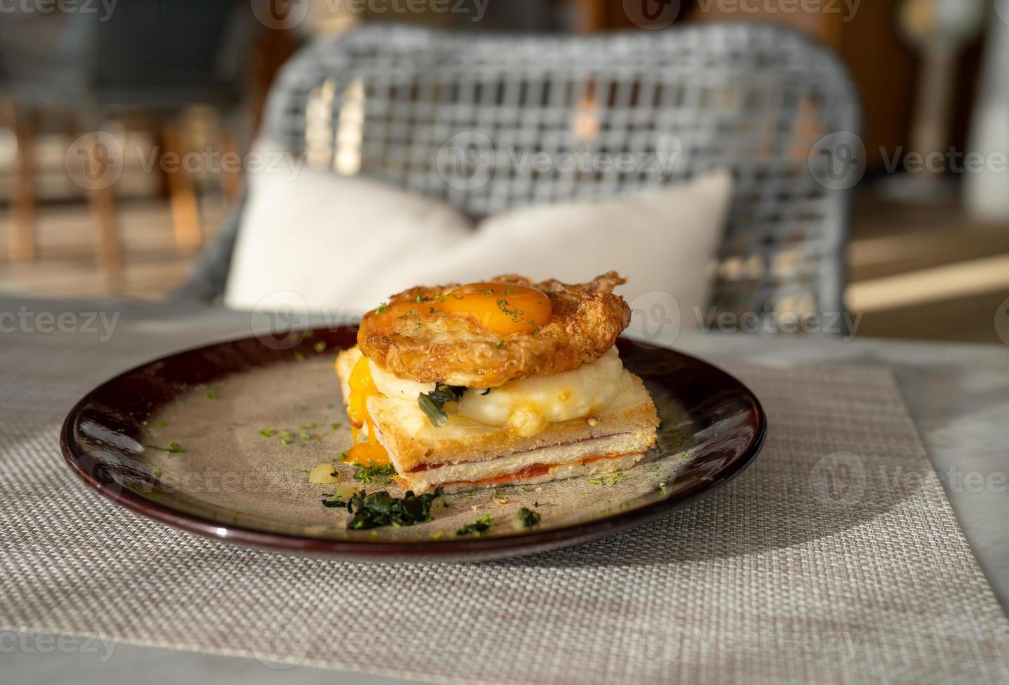 fried egg top on ham and spinach sandwiches on dish for breakfast on the table in the morning photo