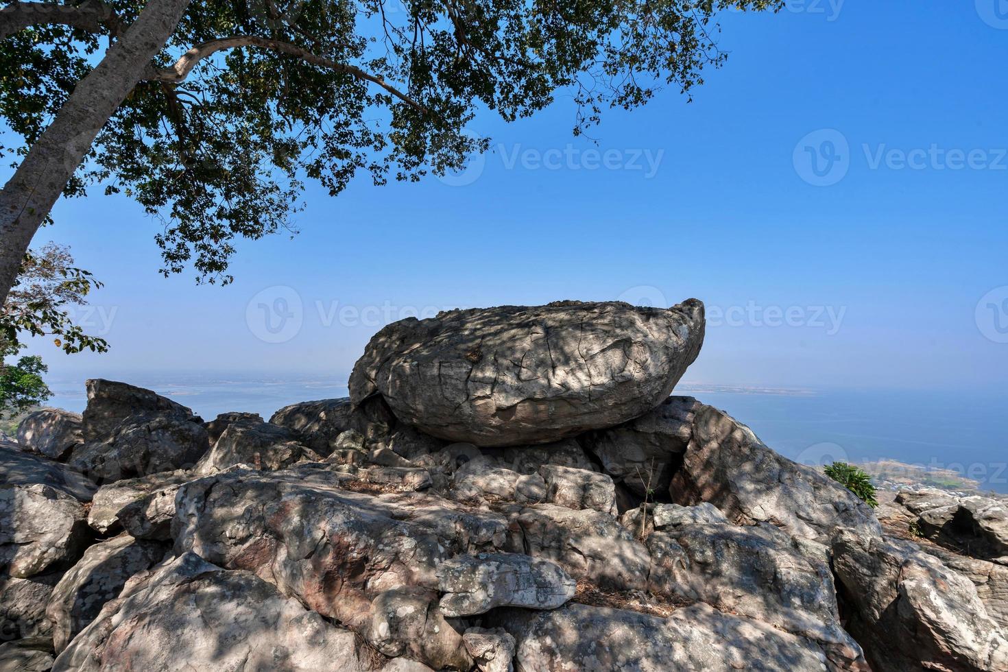 big rock rock viewpoint of mountain peak under tree branches in misty air blue sky photo