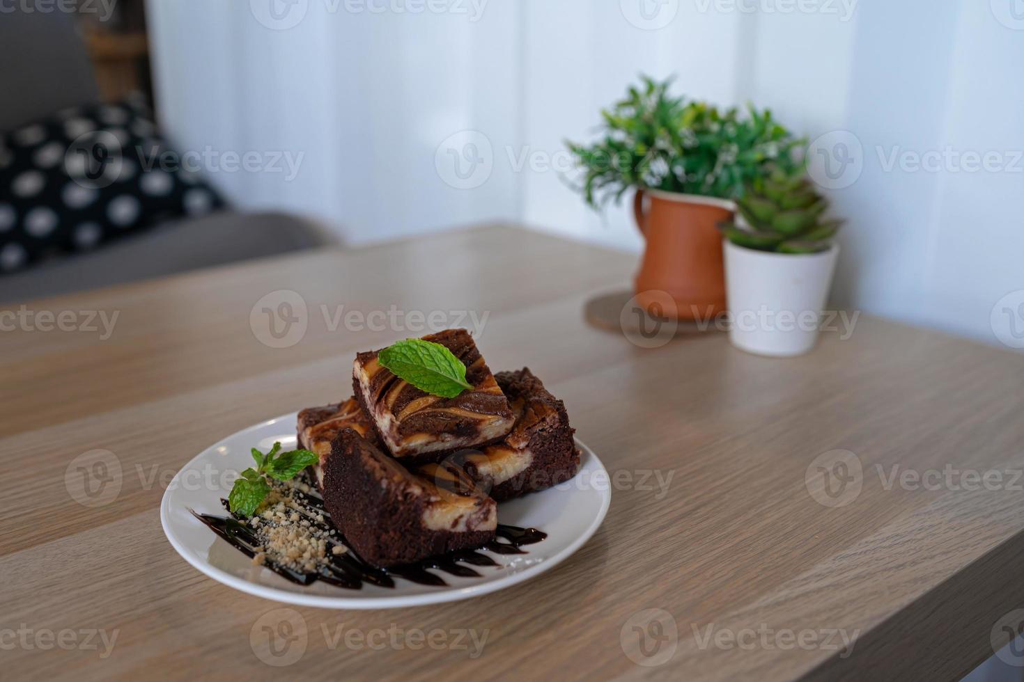 chocolate brownie with sauce and nuts decorated with mint leaf on cozy wooden table photo