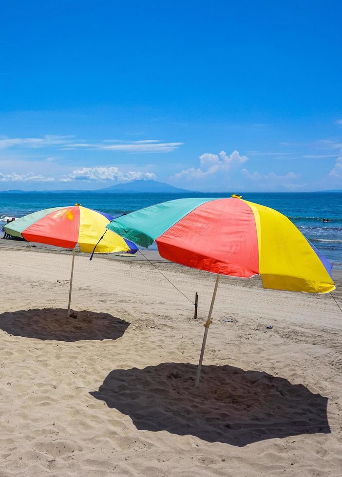 Colorful umbrella on the sand beach under blue skies. Summer vacation travel. Tropical holiday travel. Free photo