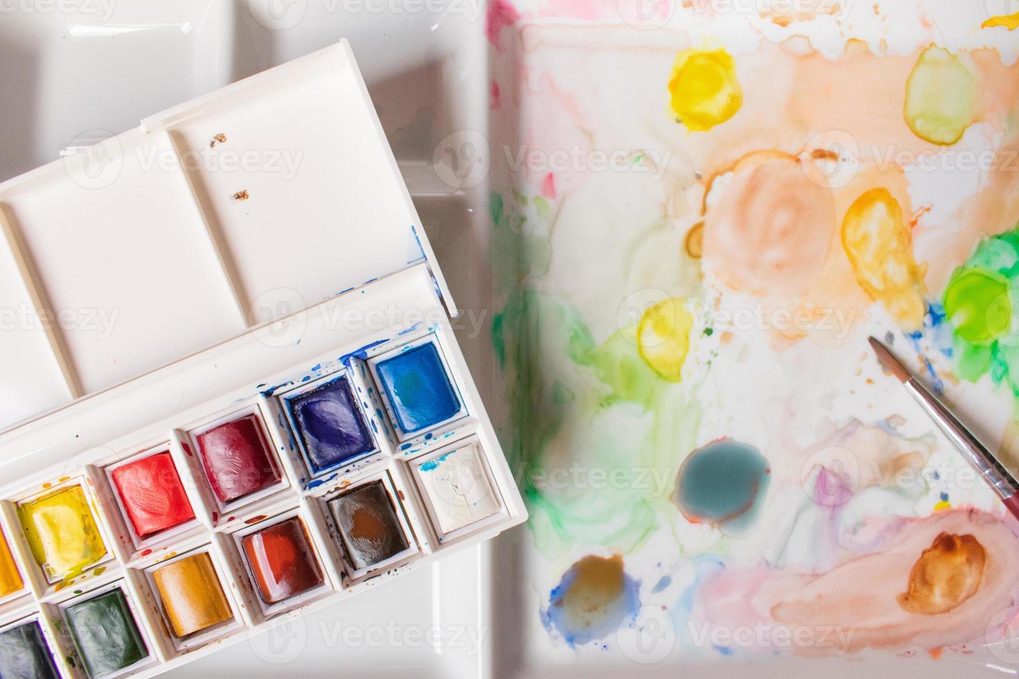 box of watercolors on a paint-stained palette photo