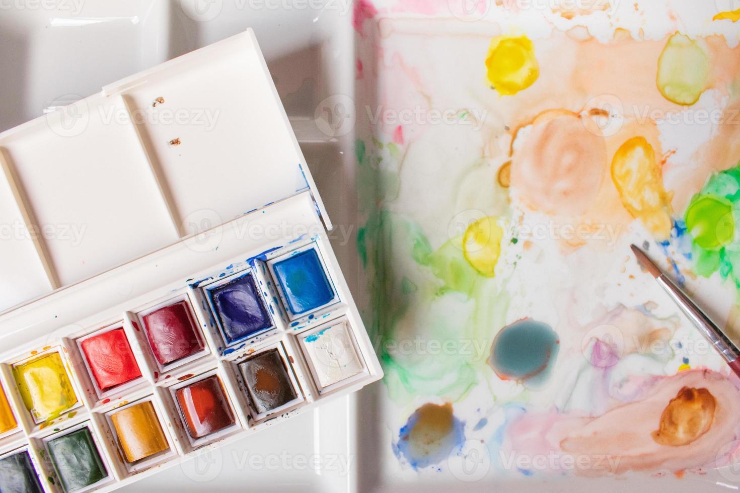 caja de acuarelas en una paleta manchada de pintura foto