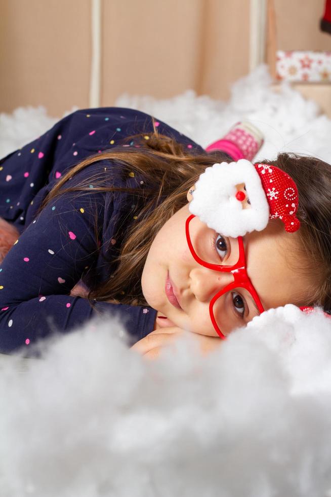 Little girl wearing santa glasses and making faces photo