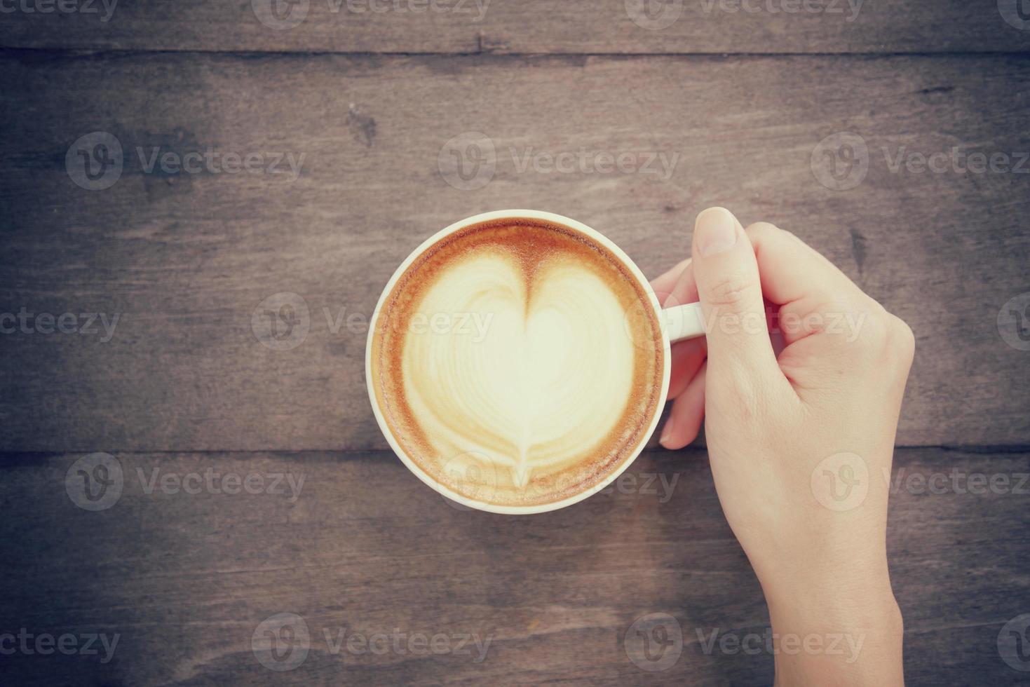 hand and cup of coffee latte art with vintage color tone photo