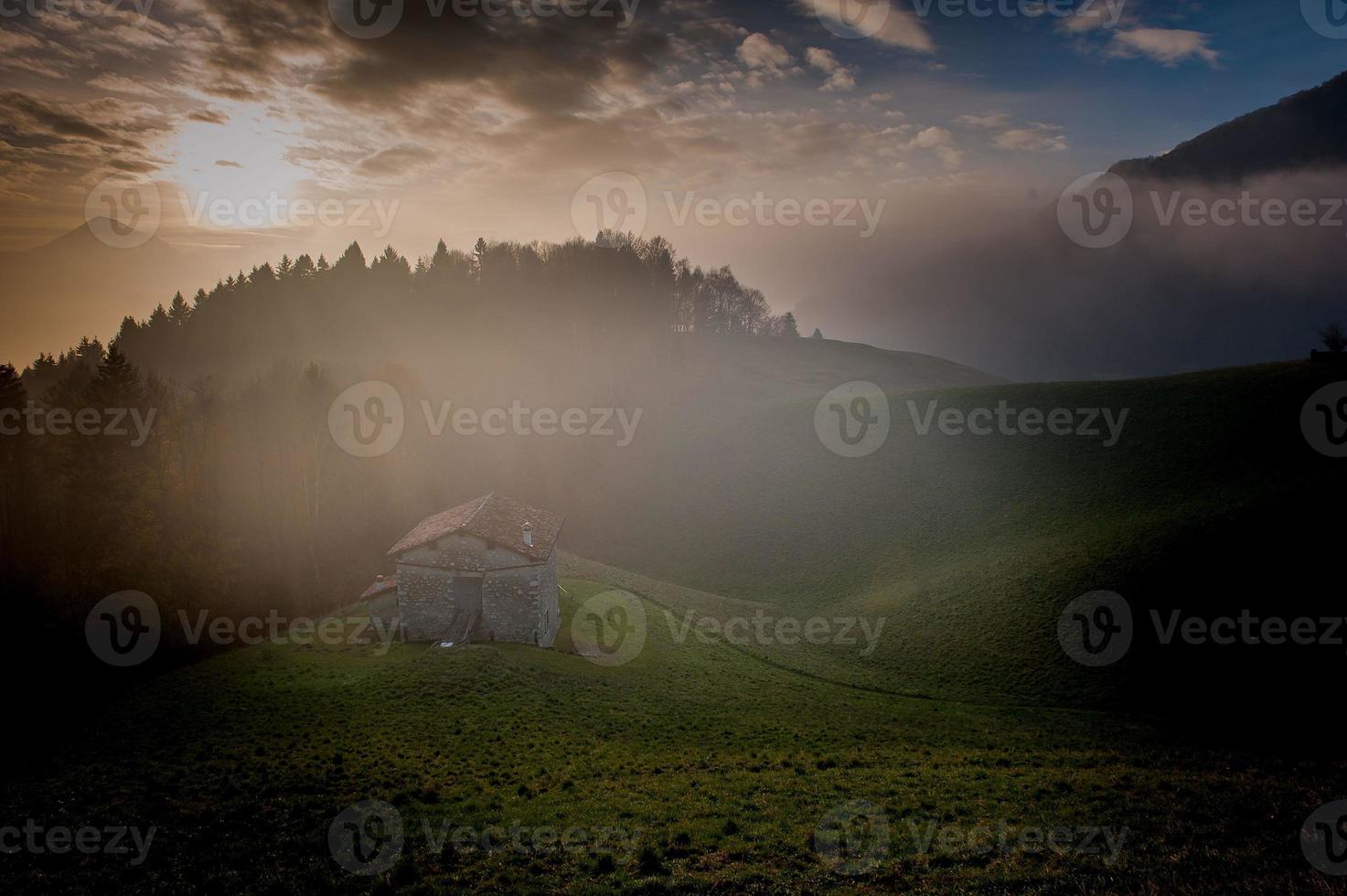 Hill with cottage surrounded by trees in autumn photo