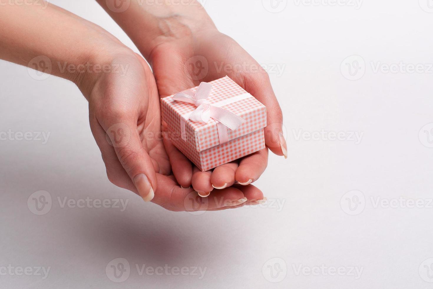 Female hand holding a gift with a bow. photo