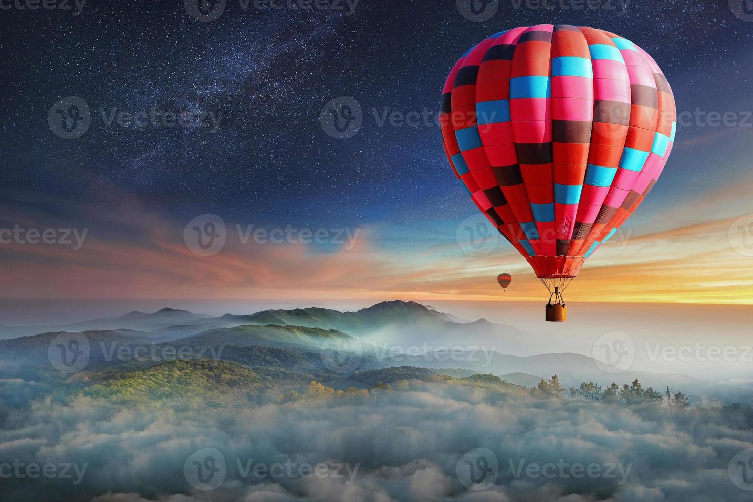 Colorful hot-air balloons flying over the mountain with with stars. Beautiful mountains landscape with clouds at sunset photo