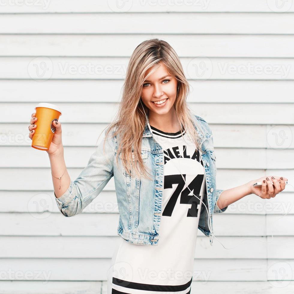 Pretty happy hipster girl enjoys music and drinks coffee. photo