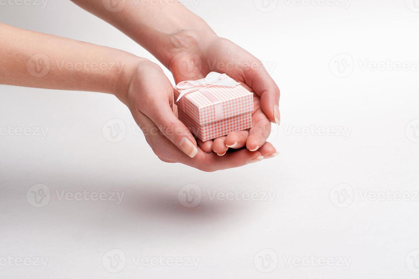 Female hand holding a gift with a bow. photo