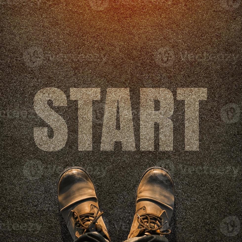 A pair of feet on a tarmac road with white print of the word start for the concept of starting point. Start concept background. photo