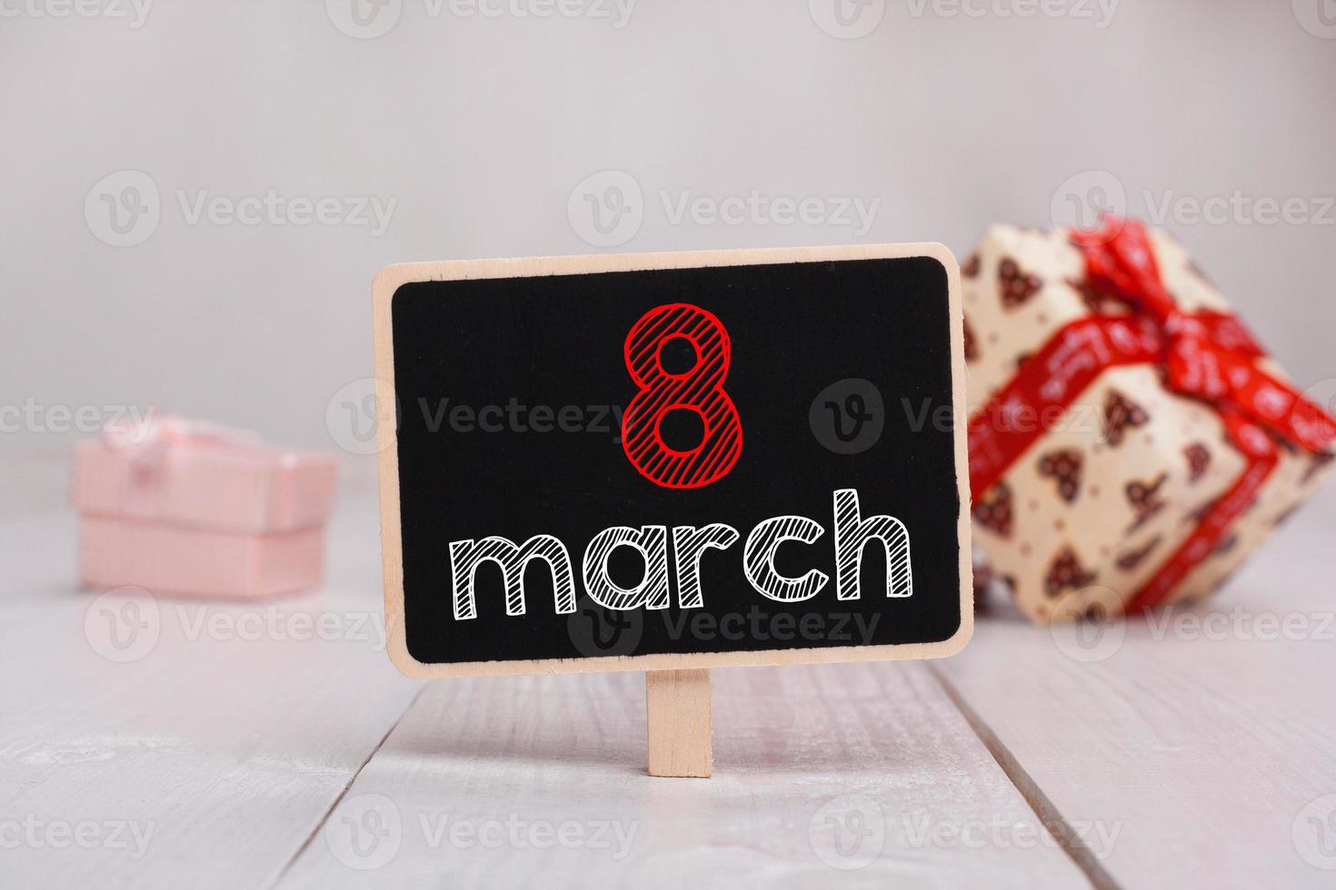 8 March message written on little chalkboar. Background with gifts. photo