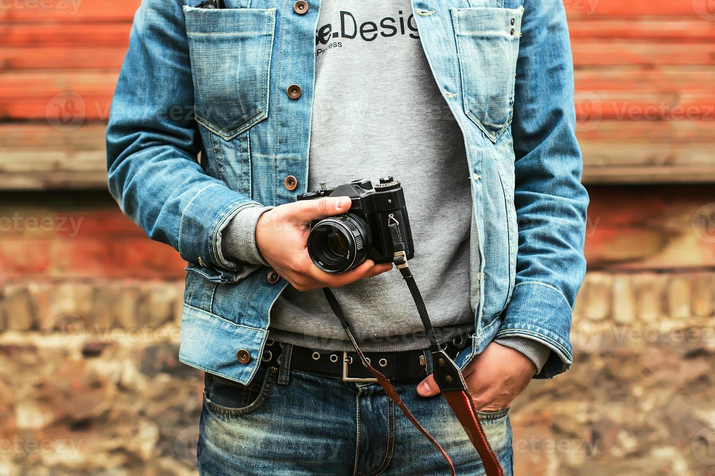 Stylish hipster photographer in fancy denim clothes holding a camera photo