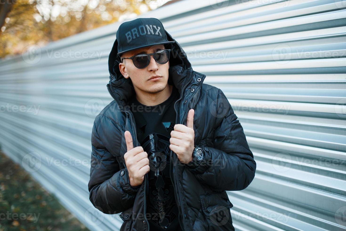 chico guapo con un elegante vestido negro sobre un fondo de pared de metal. foto