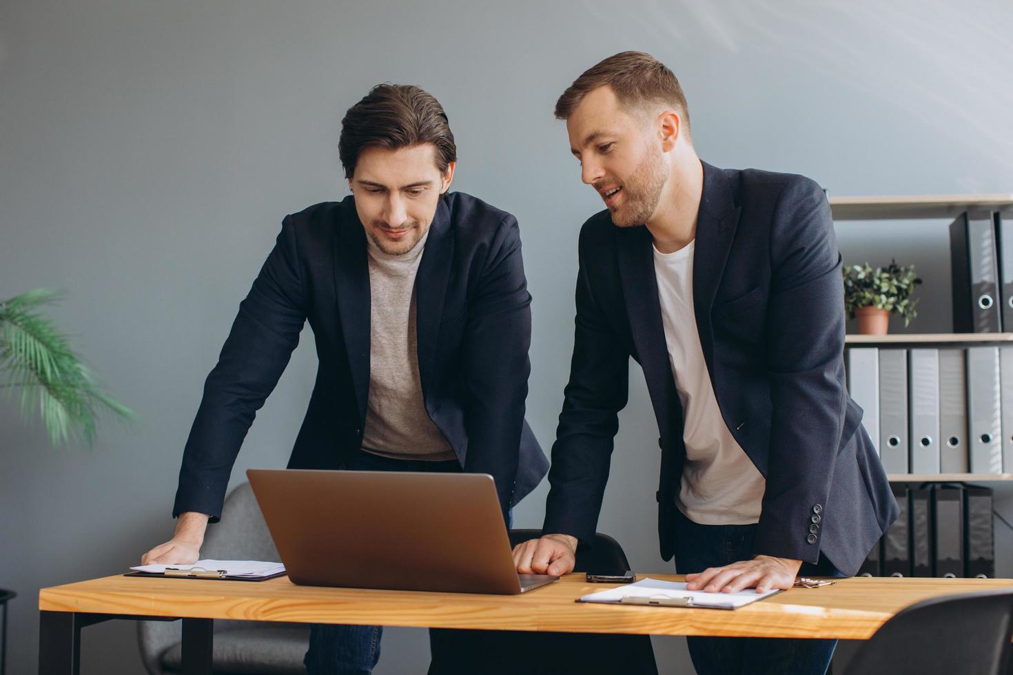 Business teamwork - two corporate businessmen working together on laptop photo