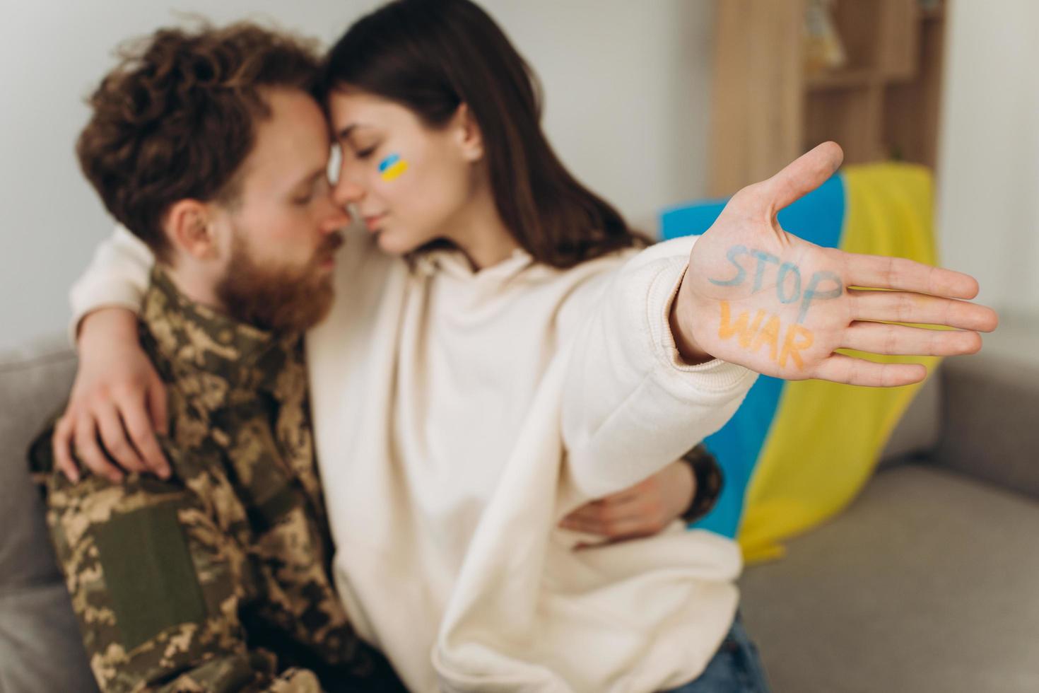 Ukrainian soldier in military uniform with his girlfriend showing a hand with the inscription stop war photo