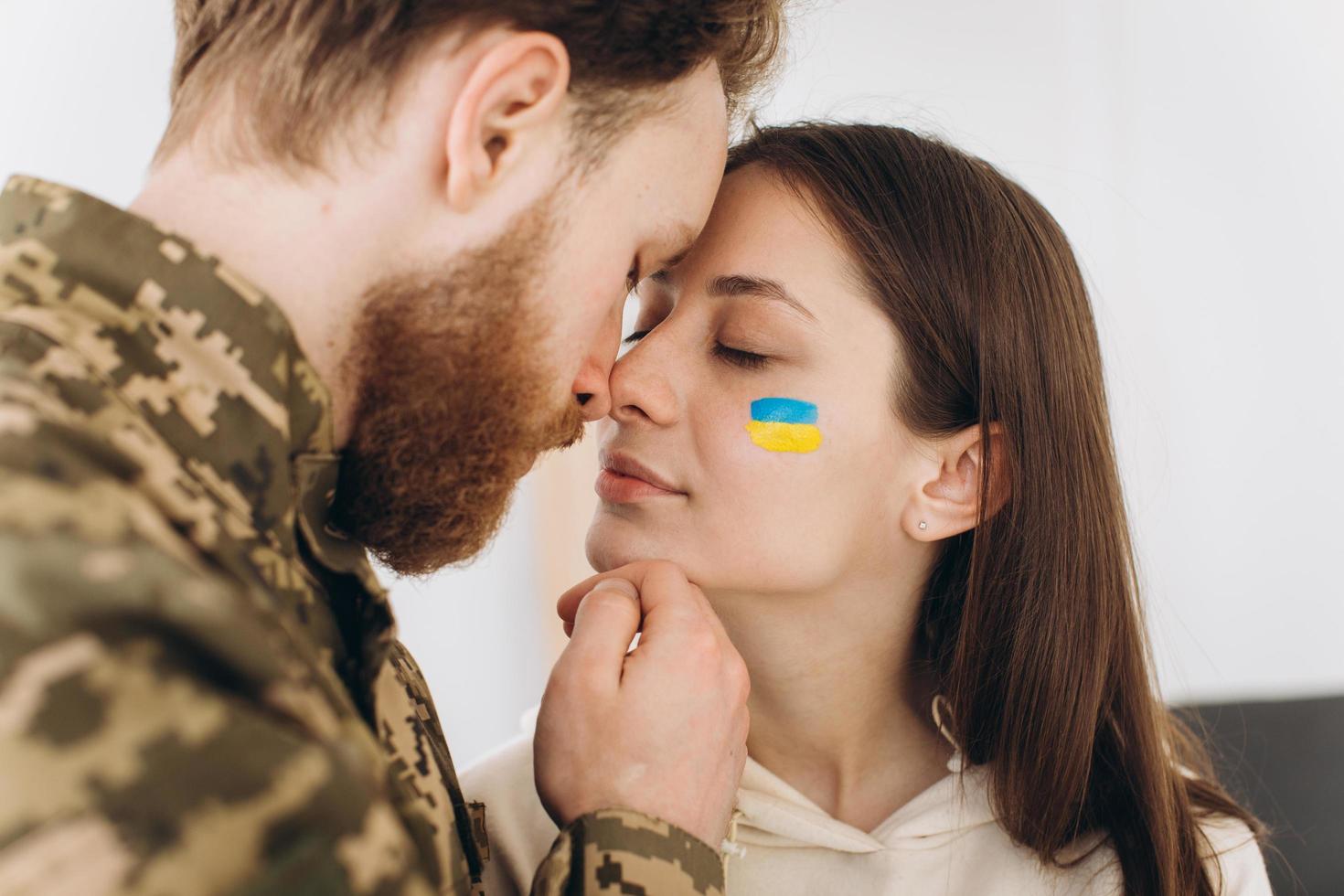 Ukrainian couple, military bearded man in uniform kisses his girlfriend at home photo