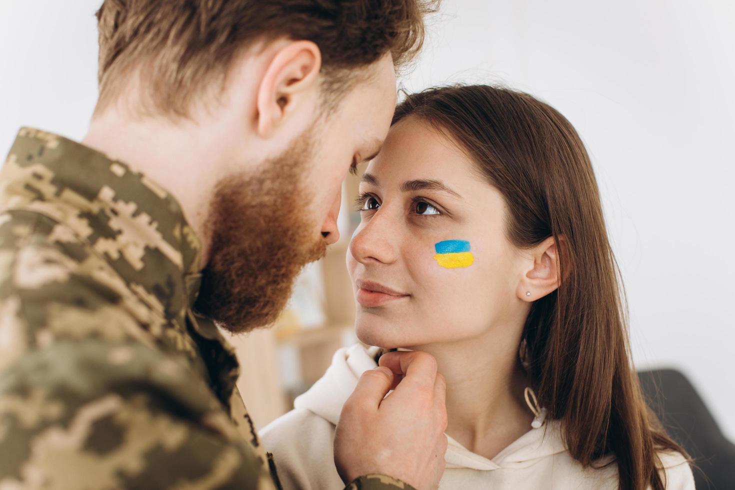 Ukrainian couple, military bearded man in uniform kisses his girlfriend at home photo