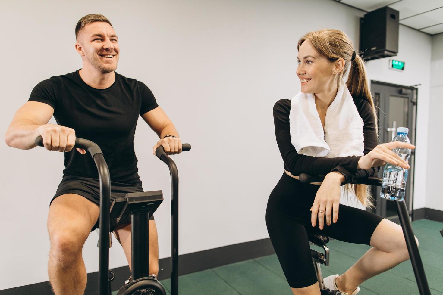 joven y mujer usando bicicleta de aire para hacer ejercicio cardiovascular en el gimnasio de entrenamiento cruzado foto