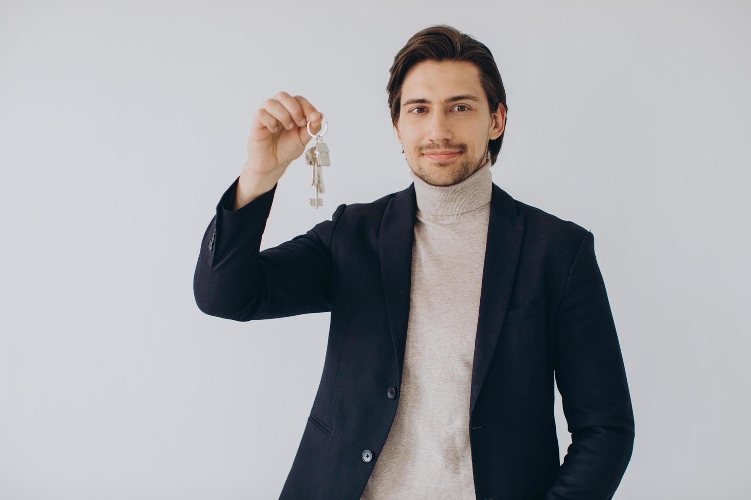 retrato de un alegre agente inmobiliario profesional que sostiene el portapapeles y muestra las llaves en la mano, enfoque selectivo. foto