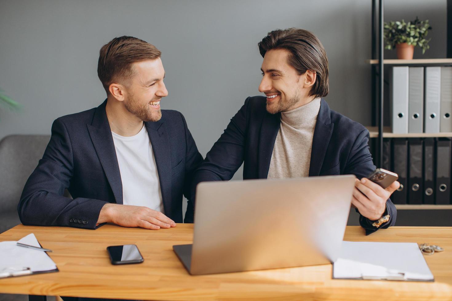 Business teamwork - two smiling corporate businessmen working together on laptop photo