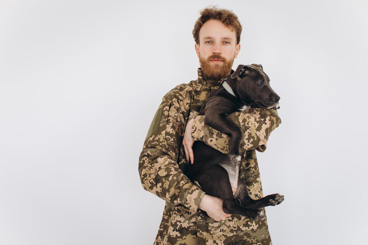 Ukrainian soldier in military uniform holds a dog in his arms on a white background photo