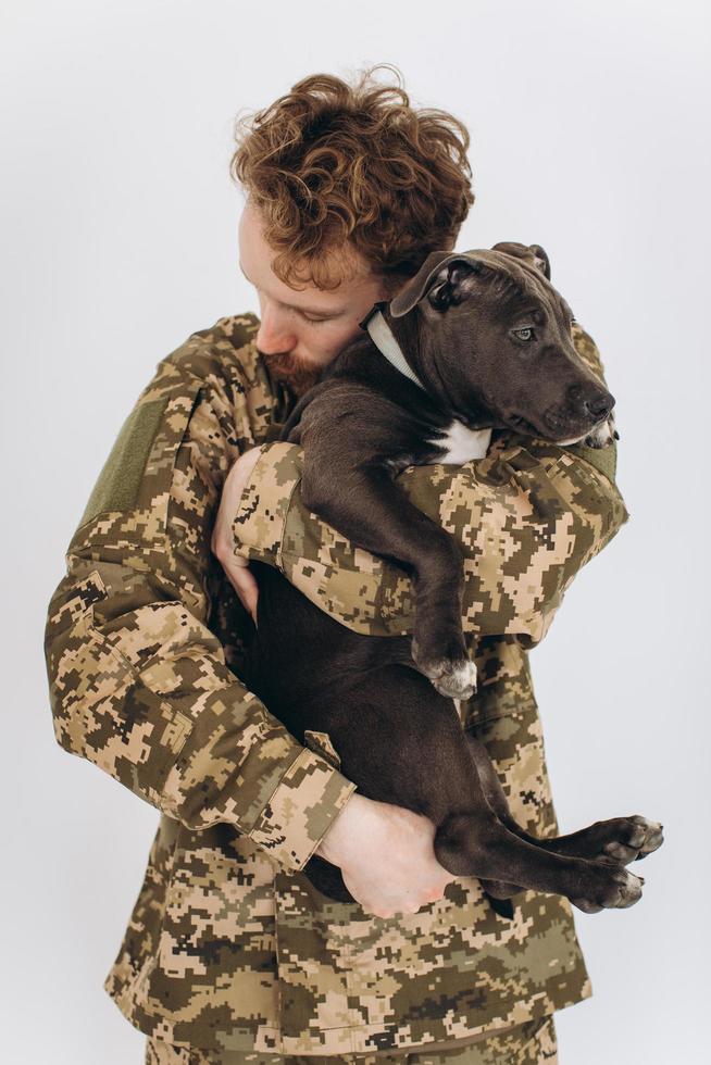 soldado ucraniano en uniforme militar sostiene un perro en sus brazos sobre un fondo blanco foto