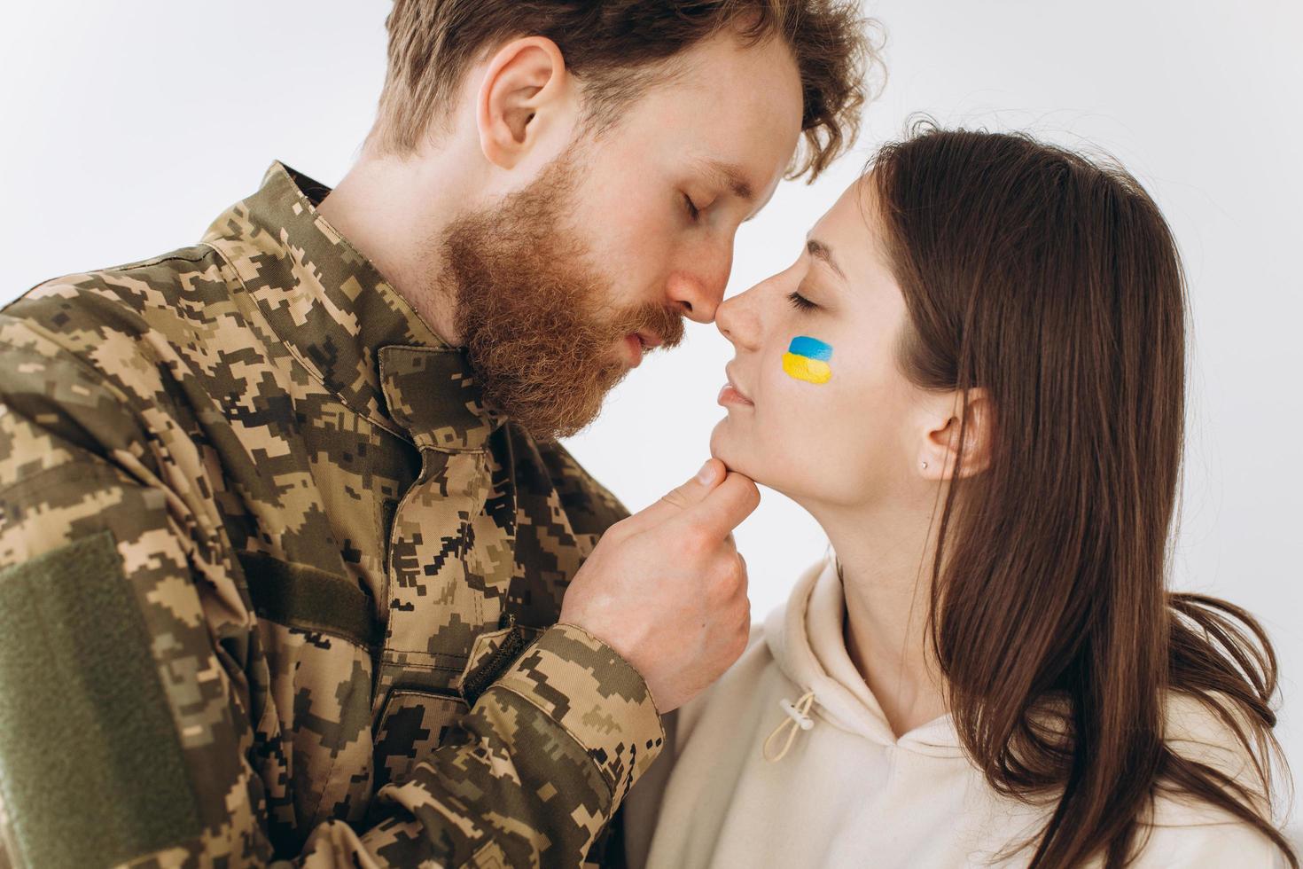 Ukrainian couple, military bearded man in uniform kisses his girlfriend at home photo