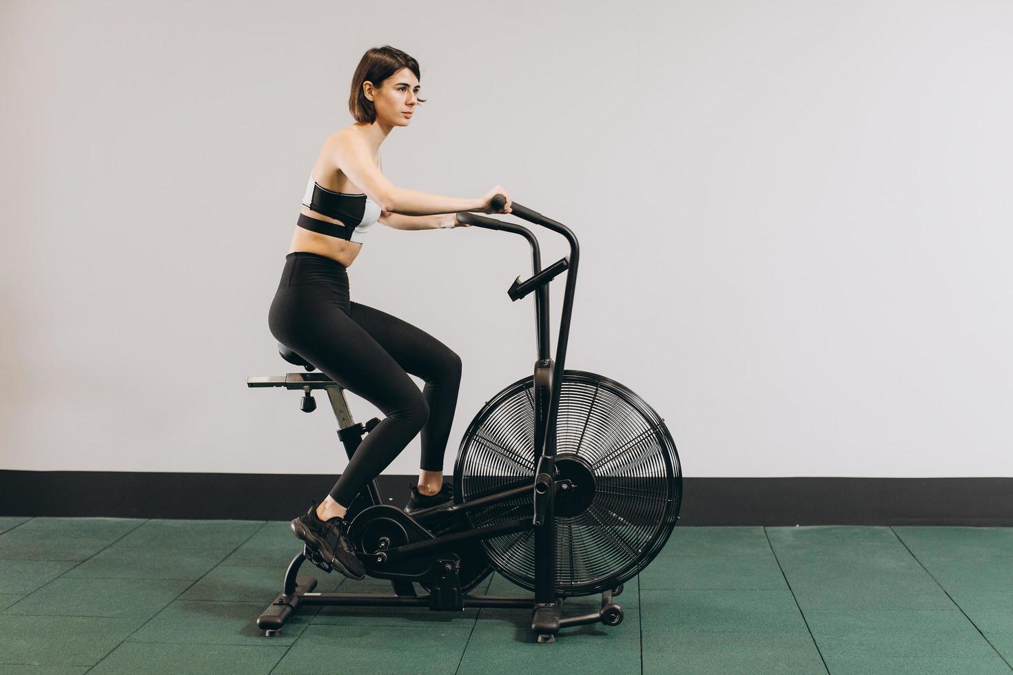 Crossfit woman doing intense cardio training on exercise air bike photo