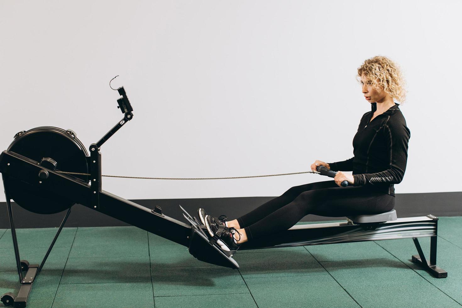 Woman exercising on rowing machine, part of circuit training warmup cardio session photo